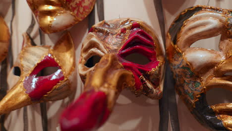 a close-up view of intricately designed venetian masks with gold, red, and black details on display in a mask shop.