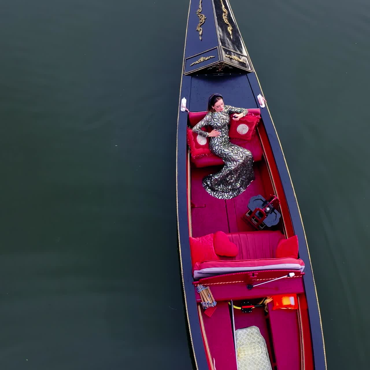 Beautiful model in gondola. Woman enjoys vacation while floating in a boat on water. Luxury woman sailing in gondola. Aerial view.