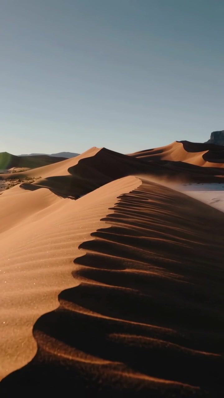 Video verticale: Vento che solleva la sabbia, drone che si muove lungo la cresta di una duna nel deserto mostrando lo scivolamento sottovento