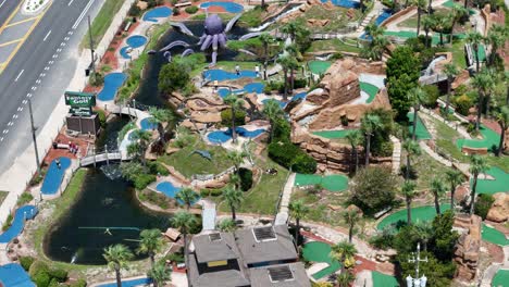 spiral panoramic drone movement over the fantasy golf at emerald falls mini golf course and entertainment place located next to a highway, panama city beach, florida, usa