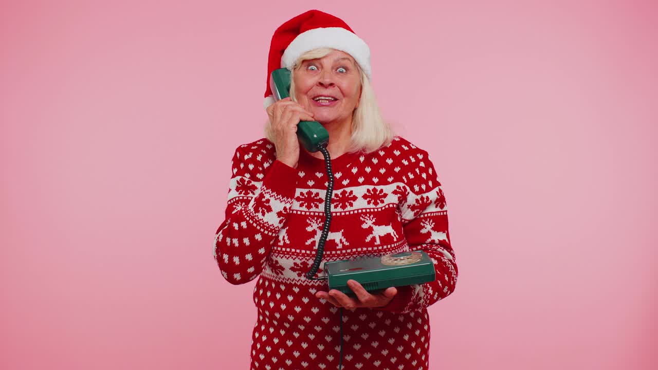 성숙한 크리스마스 할머니 여성은 80년대의 유통 전화로 이야기하고 있습니다.