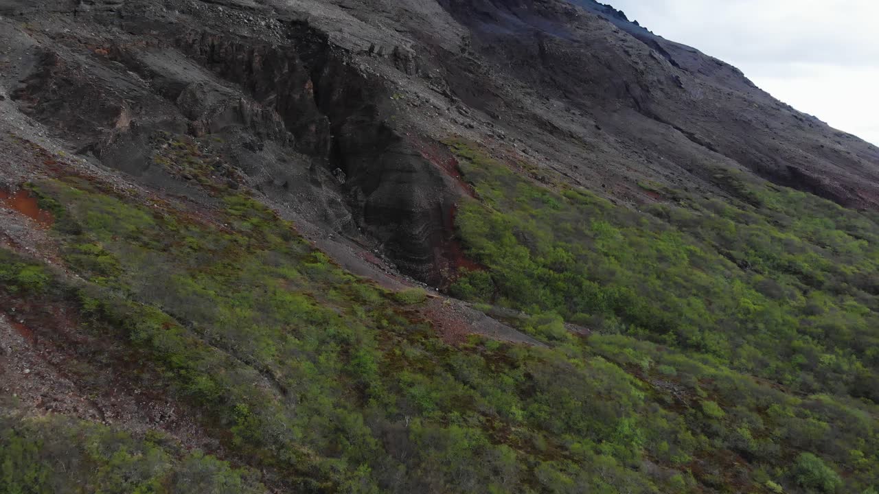 vista aérea que muestra la entrada de una cueva a una montaña majestuosa ubicada en las tierras altas islandesas-1