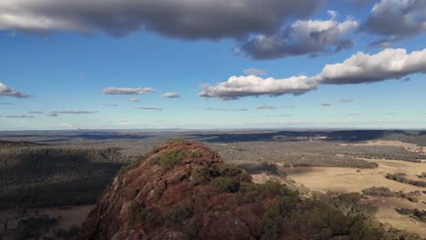 drone camera glides over timor rock, revealing expansive rural landscapes under partly cloudy skies with natural daylight and smooth forward movement