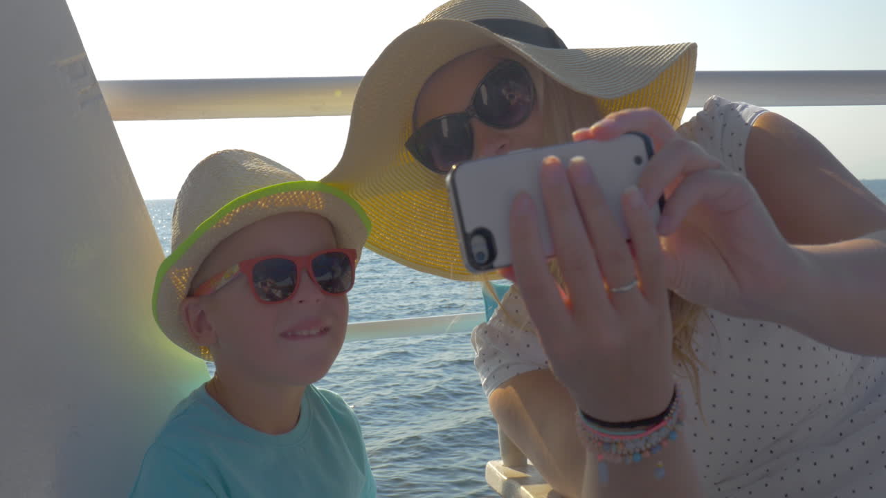 madre e hijo tomando selfies durante un viaje por mar