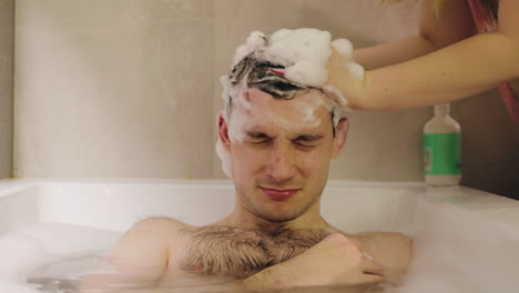 person washing someone else's hair in a bath