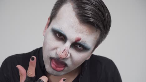 man with scary face paint sticking out tongue, closeup portrait