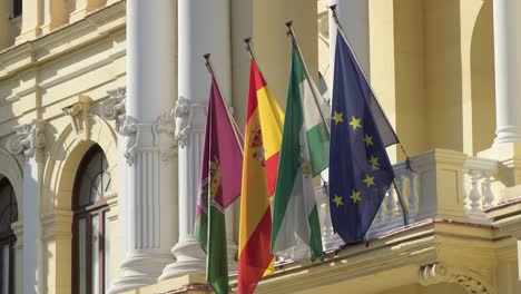 flags of europe, spain, andalusia and malaga, hanging in town hall at sunset