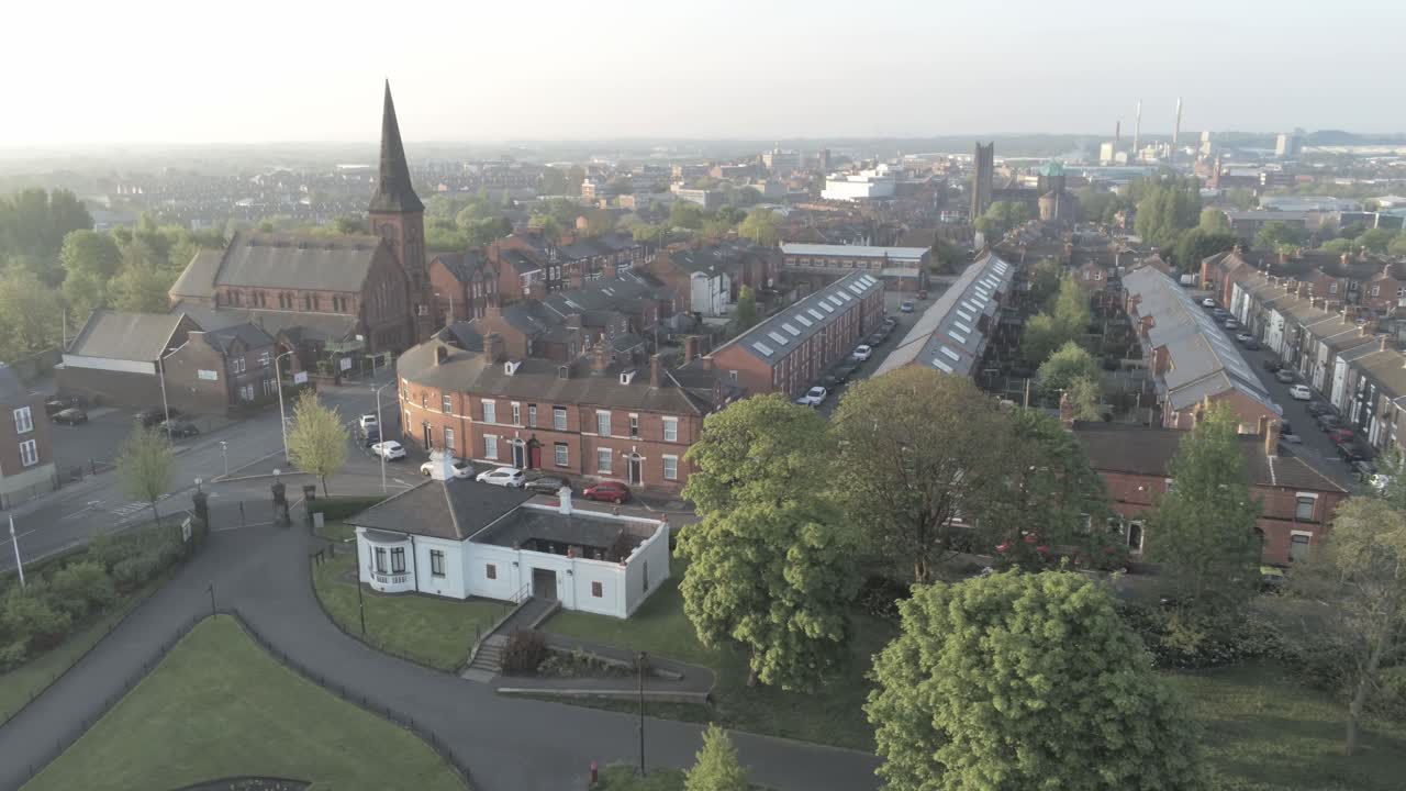 drone dolly vista izquierda a través de la iglesia británica campanario y casas del parque público de la ciudad al amanecer