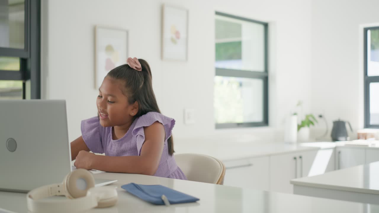 Bambino afroamericano che risponde a una domanda, alzando il braccio, digitando sul laptop in cucina, con spazio per il testo