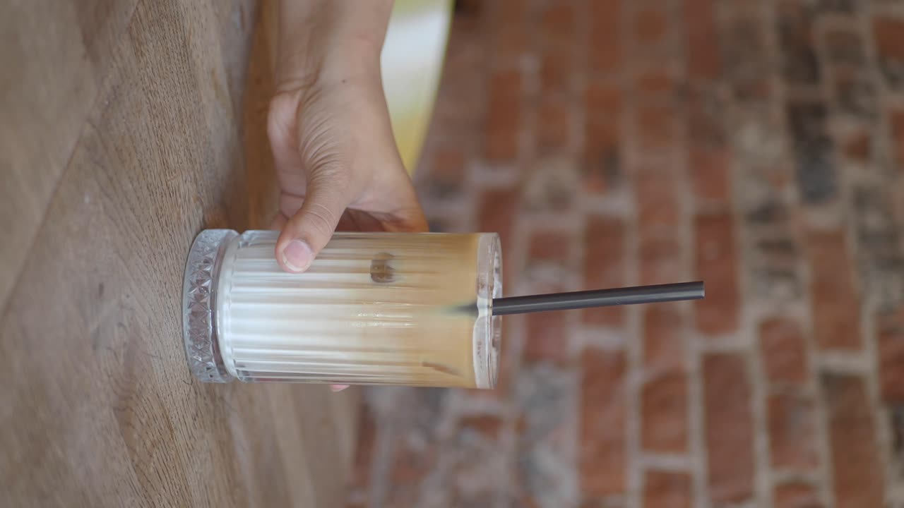 Hand interacting with a glass of iced coffee