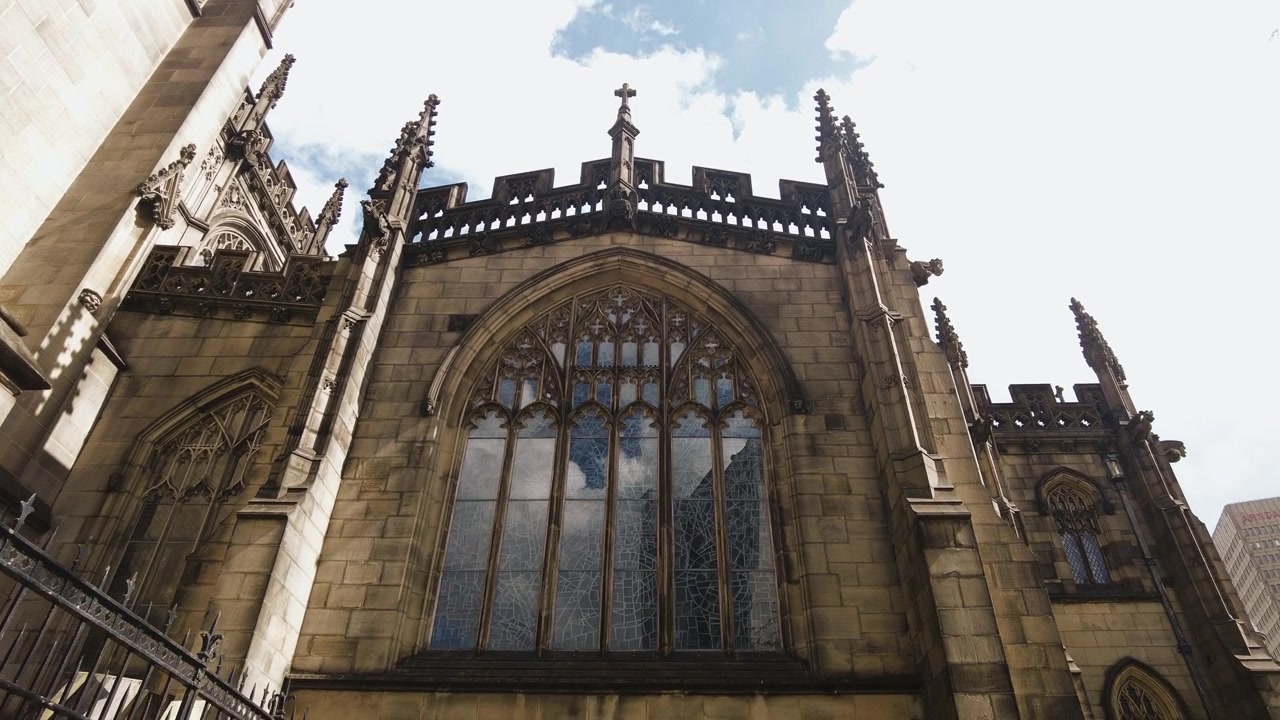 Esterno della cattedrale di Manchester, parete con vetrate colorate della chiesa vista dall'esterno in primo piano.