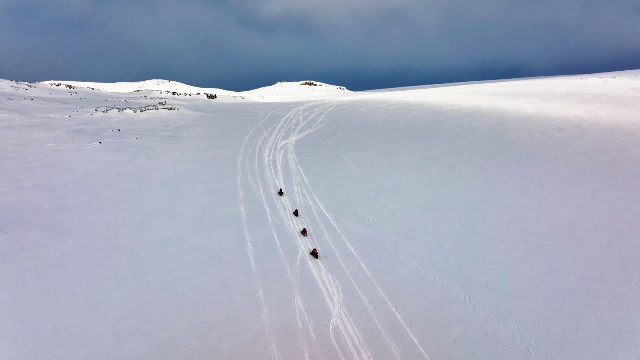 Aerial panoramic view of people riding snowmobiles on the icy ground of Myrdalsjokull glacier in Iceland