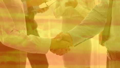 Animation-of-businesswoman-and-businessman-shaking-hands-in-an-office-with-orange-clouds-