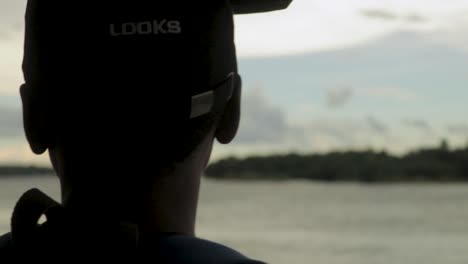 an abstract rack focus shot of a young african man looking out from the side of a boat, appreciating the mighty zambezi river and beautiful scenic landscape surrounding the victoria falls, zimbabwe