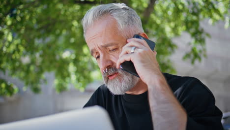 primer plano casual anciano hablando teléfono inteligente. ocupado hombre de negocios de cabello gris trabajando