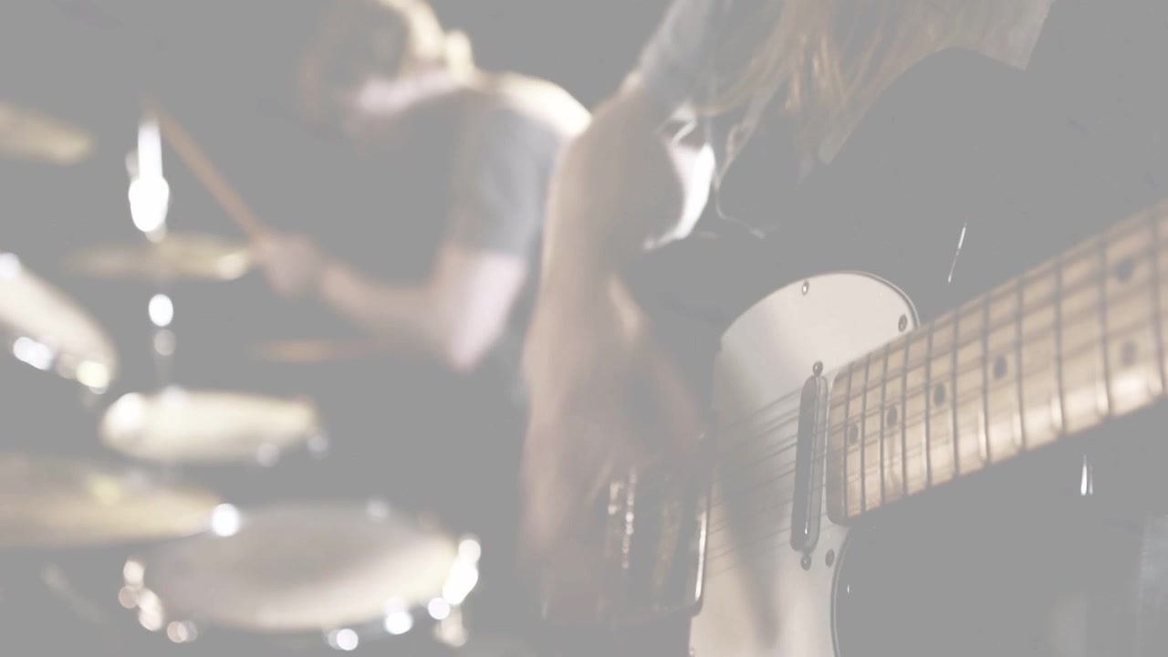 カメラがワイドになり、ギタリストがフレットを押さえピッキングし、ドラマーがドラムを叩くことで、音楽のテクニックを披露している。