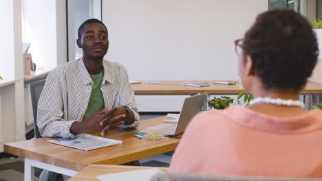 muslim young worker sitting on the table while talking with businesswoman 1