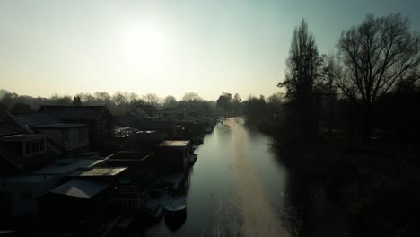 Gente-Distante-En-Silueta-Patinando-Sobre-Hielo-En-Un-Río-Congelado-Al-Amanecer-En-Hendrik-ido-ambacht,-Países-Bajos