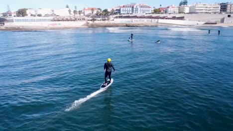 aerial back view of a foiler riding a wave toward the beach in europe
