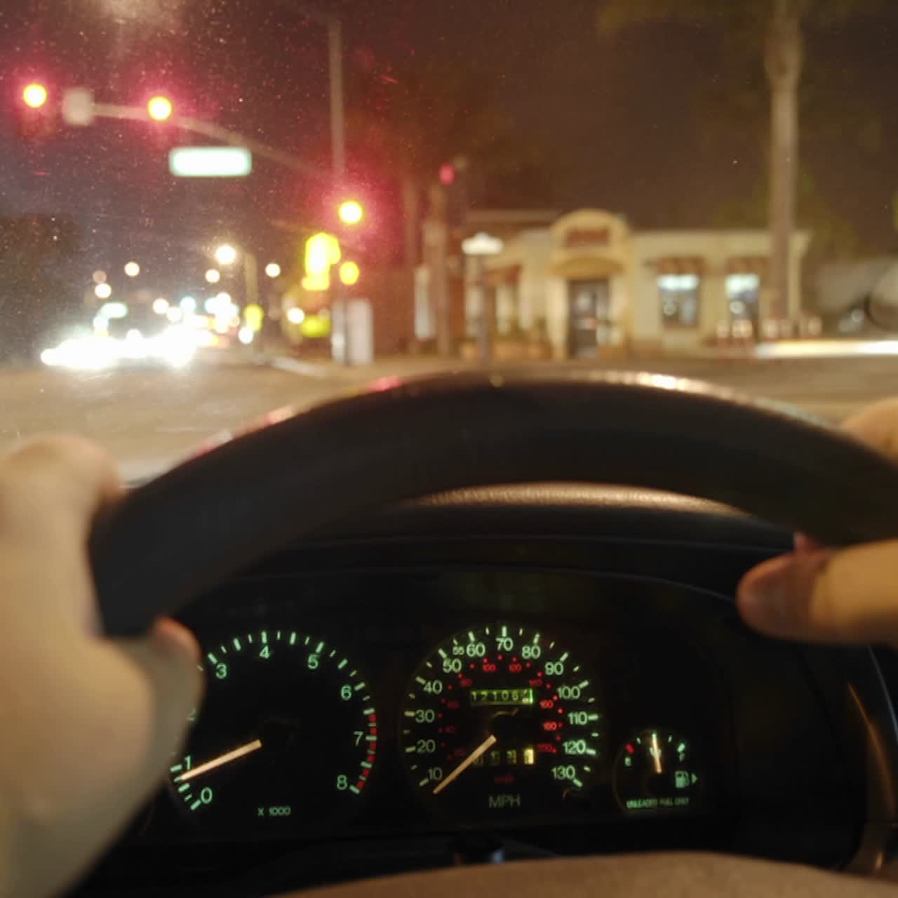 한 사람이 밝은 도시 거리를 통해 차를 운전한다