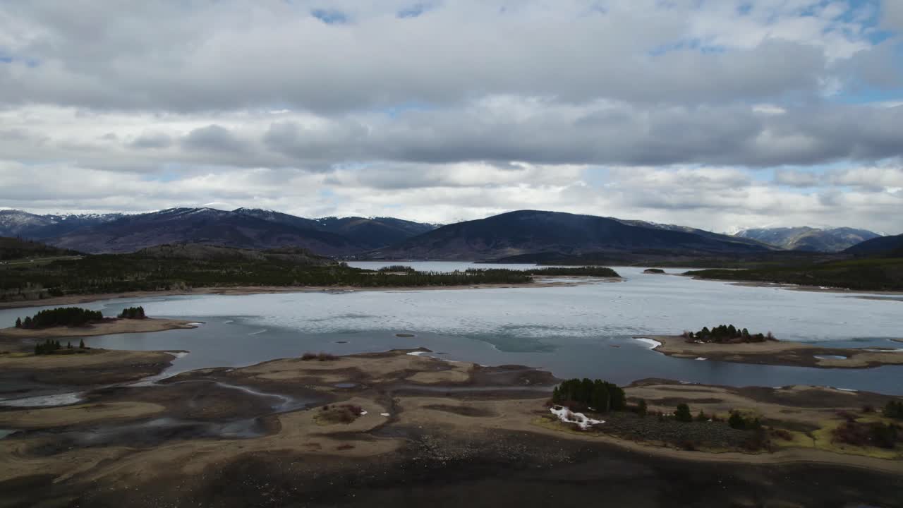 Aerial shot reveals expansive landscape with snow covered trees and distant mountains. Escaping the city life for time in nature.
