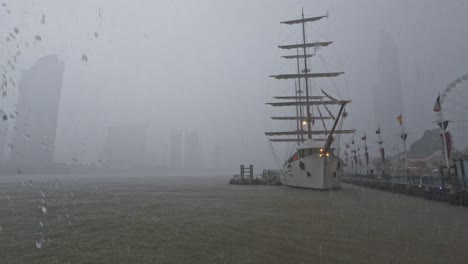 heavy rain storm strike on the dark grey misty sky over chao phraya river area in bangkok,thailand - view from the dock