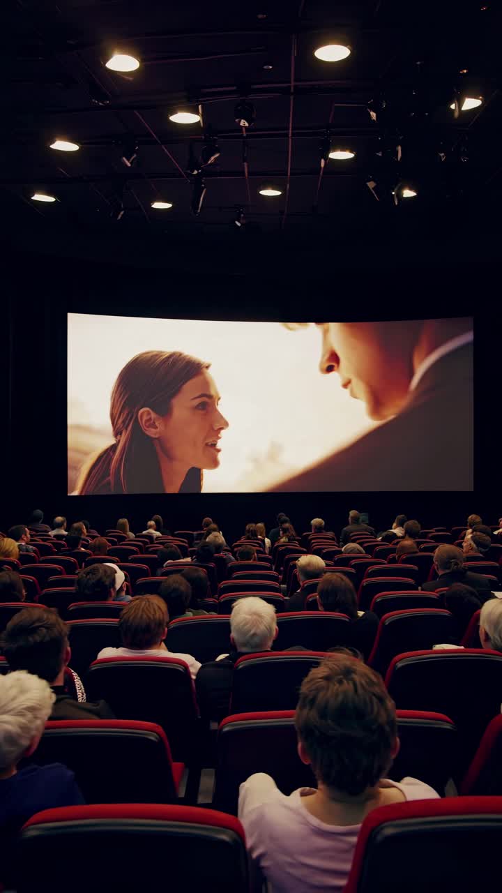 Wide-angle shot of a cinema audience watching a video on a large screen, capturing the immersive