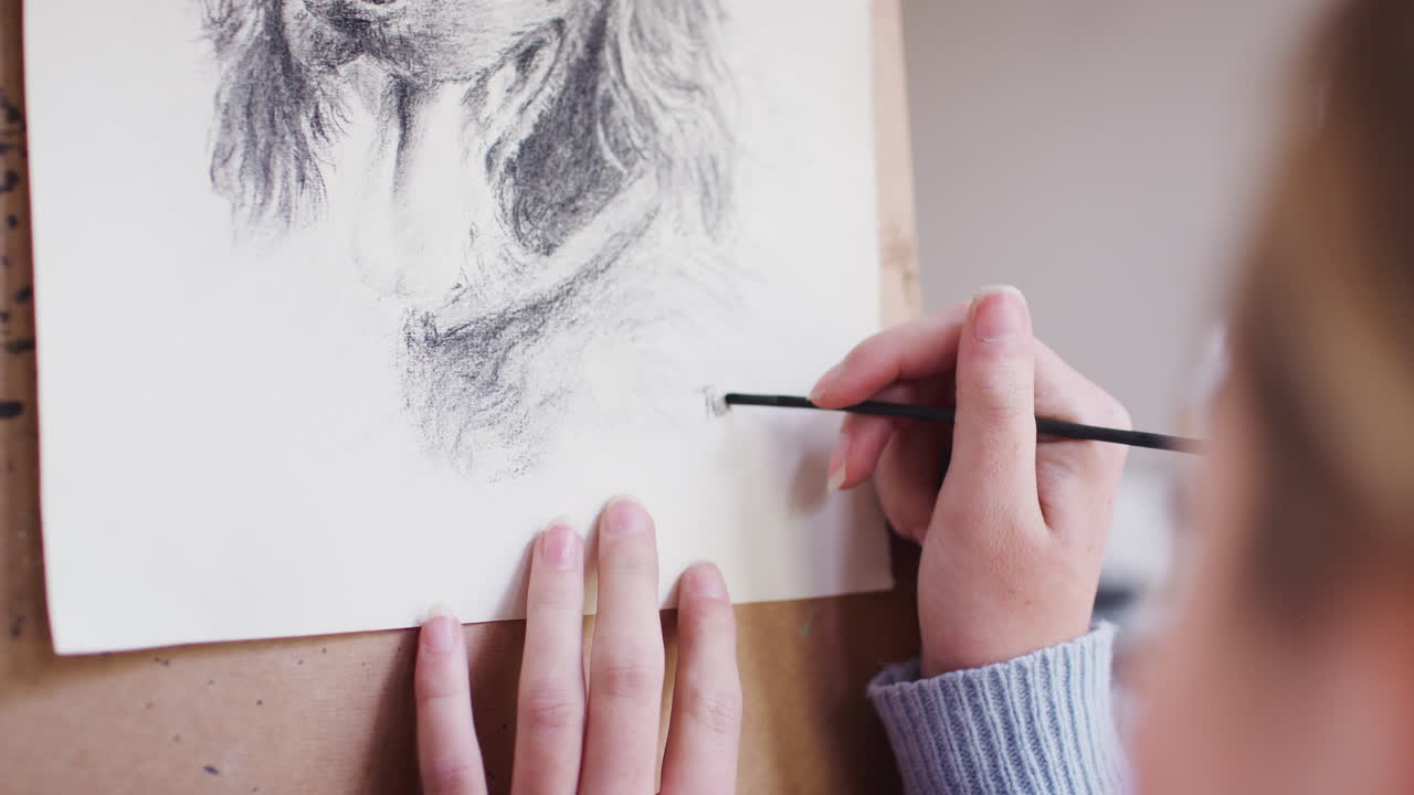 близкий взгляд на женщину-художника, подписывающую эскиз собаки на уголе