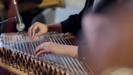 a woman playing on zither in the theatre beside a man playing oud high angle shot, close up