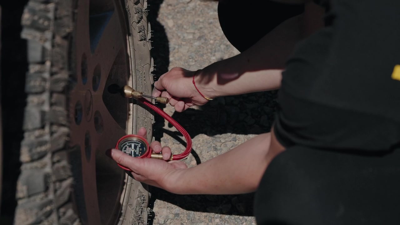 Close view of hands fitting a brass inflator chuck to an off road tire valve