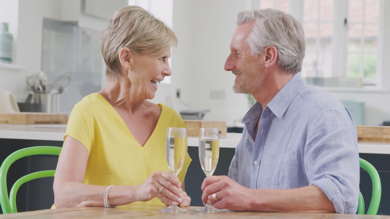 은퇴 한 부부 가 함께 집 에서  ⁇ 페인 한 잔 을 마시며 카메라 에 건배 하고 있다