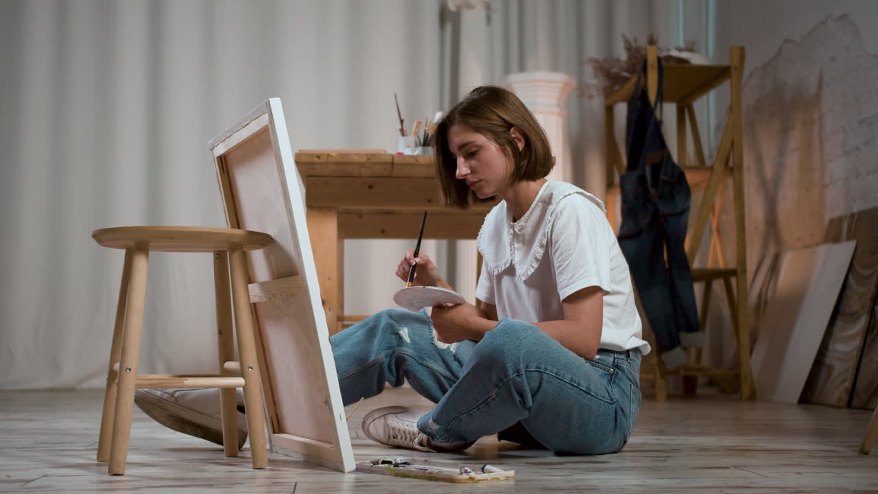 Young woman sitting on the floor with canvas