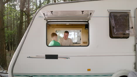 father and son playing chess sitting on the campervan bed