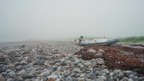 Bote-Anclado-En-La-Costa-Pedregosa-Durante-La-Mañana-Brumosa-Cerca-De-Donnmannen,-Noruega