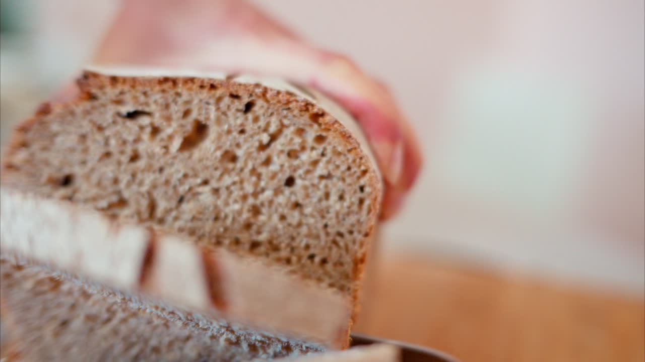 Woman cutting rye sourdough bread on a wooden cutting board