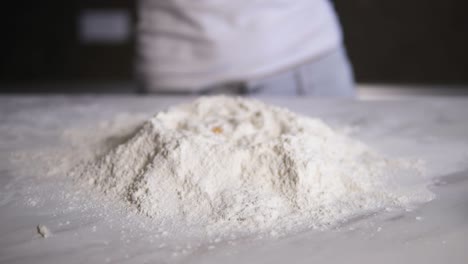 close up view the egg falling into the flour on the kitchen table. slow motion shot