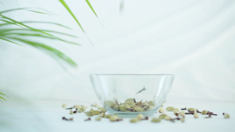 Zoom-in-shot-of-spices-mix-falling-in-a-glass-bowl-on-white-background