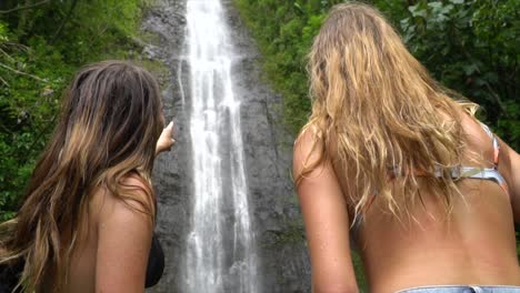 two females admire big waterfall and point to it in slow motion