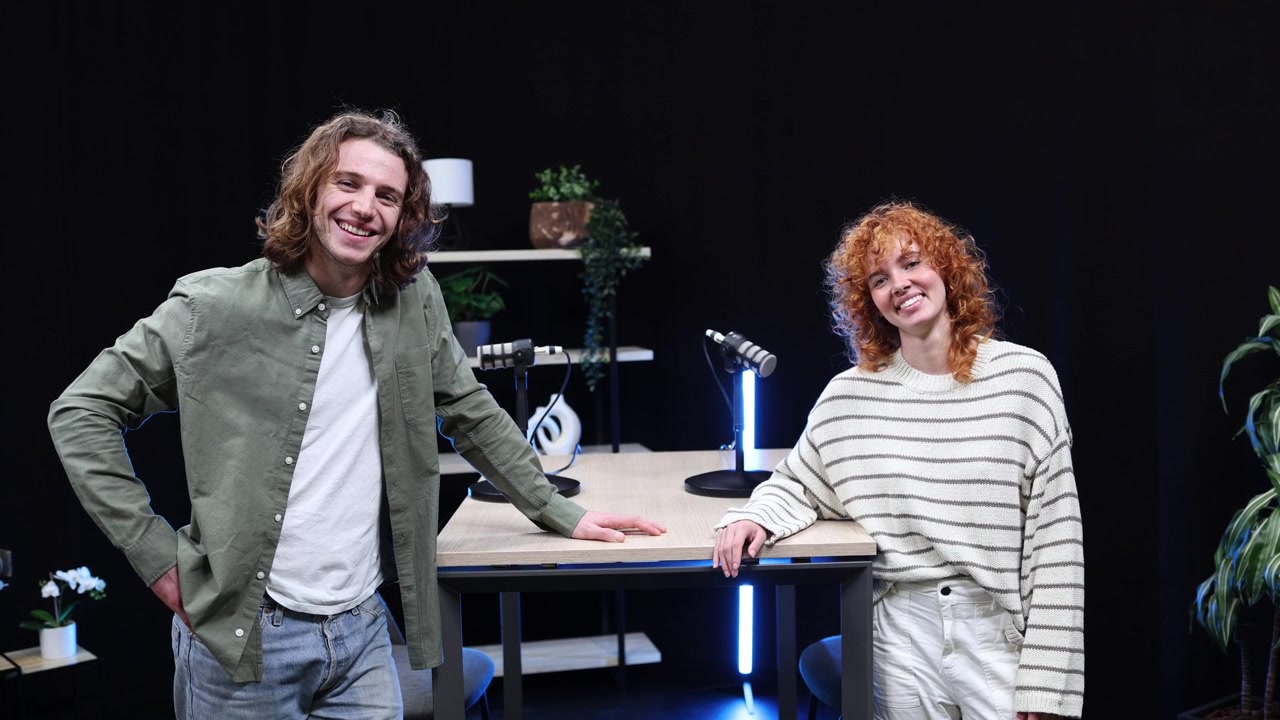 Giovane uomo e donna felici in posa in uno studio podcast