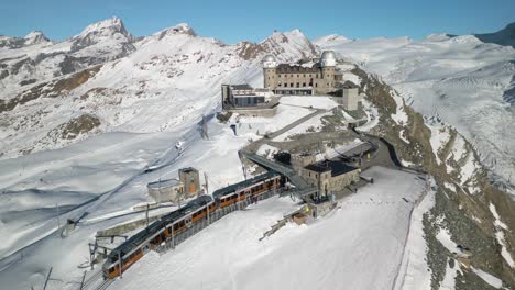 Beautiful-Drone-Shot-Above-Gornergrat-Observation-Platform-as-Train-Arrives-at-Mountain-Peak-in-Switzerland