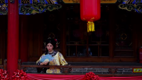 Girl-dressed-as-a-Qing-Dynasty-empress-smiles-happily-on-a-decorated-balcony-in-Pingyao,-China