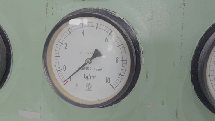 Slowmotion-nærbillede af et industrielt panel med store, vintage analoge trykmålere, der viser trykaflæsninger under udstyrets drift