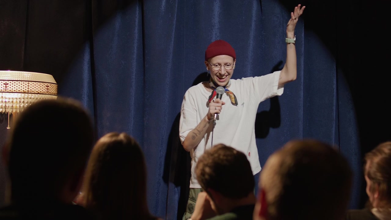 Comica donna che esegue un numero di stand-up sul palco davanti al pubblico