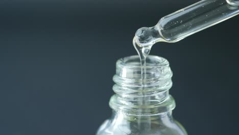 dropper filling a small glass bottle with liquid