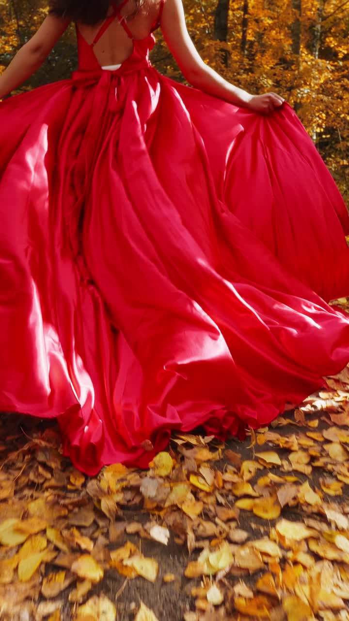 A Enchanting Walk Through Autumn: A Woman in a Flowing Red Dress Serenity Captured Among Vibrant Falling Leaves in a Picturesque Forest Setting