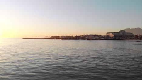 Moving-backwards-over-the-ocean-with-a-harbour-in-the-distance