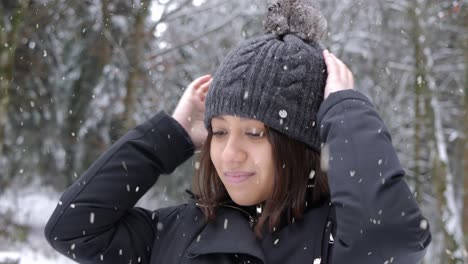 beautiful female putting on winter hat during heavy snowfall