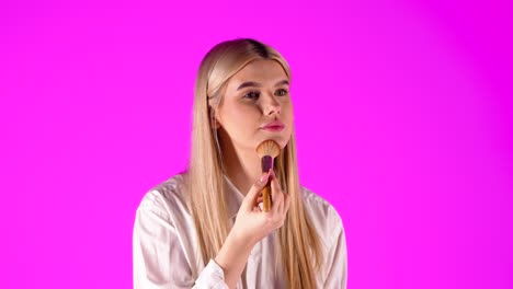 attractive cute woman is styling herself with makeup, purple studio background