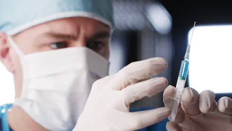 male healthcare worker flicking barrel of syringe, close up