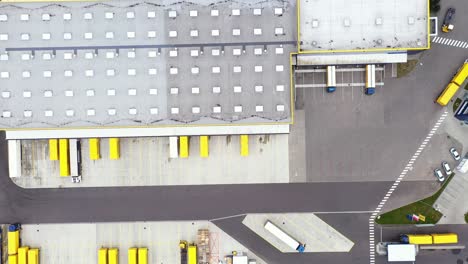 Aerial-Shot-of-Industrial-Warehouse-Storage-Building-Loading-Area-where-Many-Trucks-Are-Loading-Unloading-Merchandise